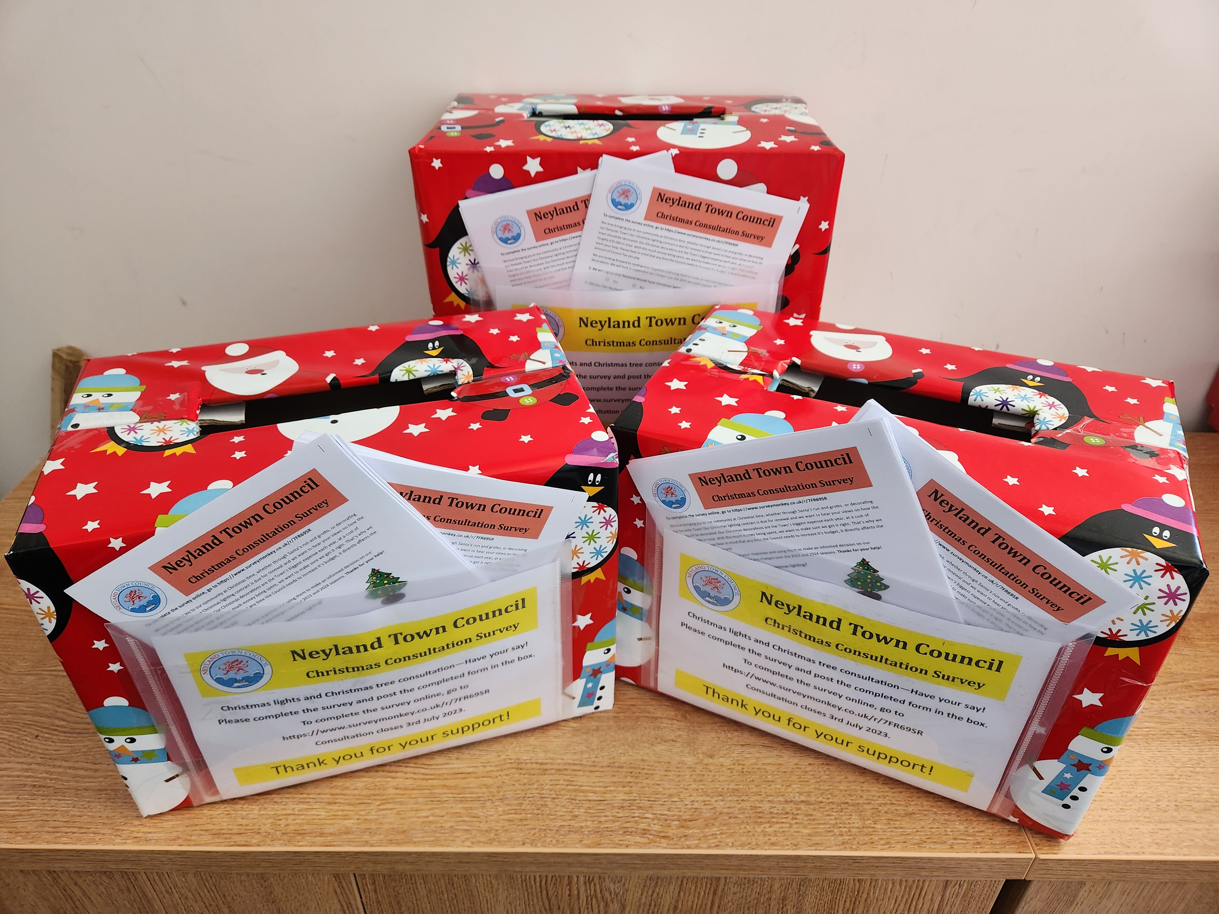 A photo of three bright red survey collection boxes with example surveys on show.